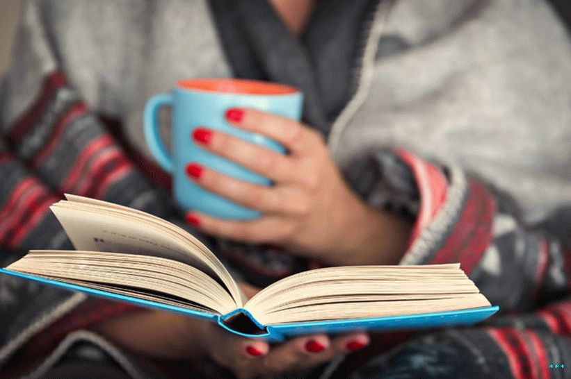 Kitap okuyarak battaniyeye sarılmış bir kadının stok fotoğrafı.